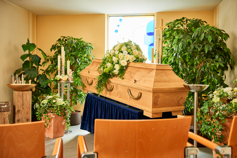 Abschiedsraum - Raum mit Blumen dekoriert, in der Mitte steht der Sarg, davor stehen Stühle